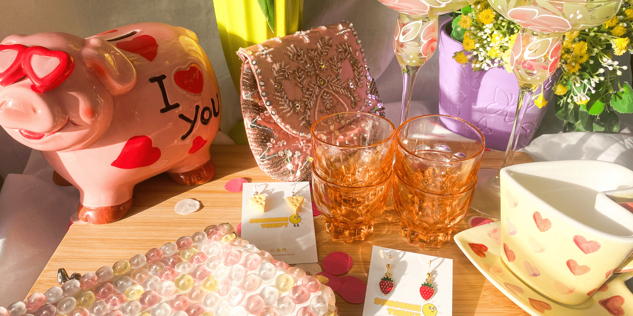 collection of second hand womens accessories and homeware including a piggy bank, pink shoulder bag, heart shaped teacup