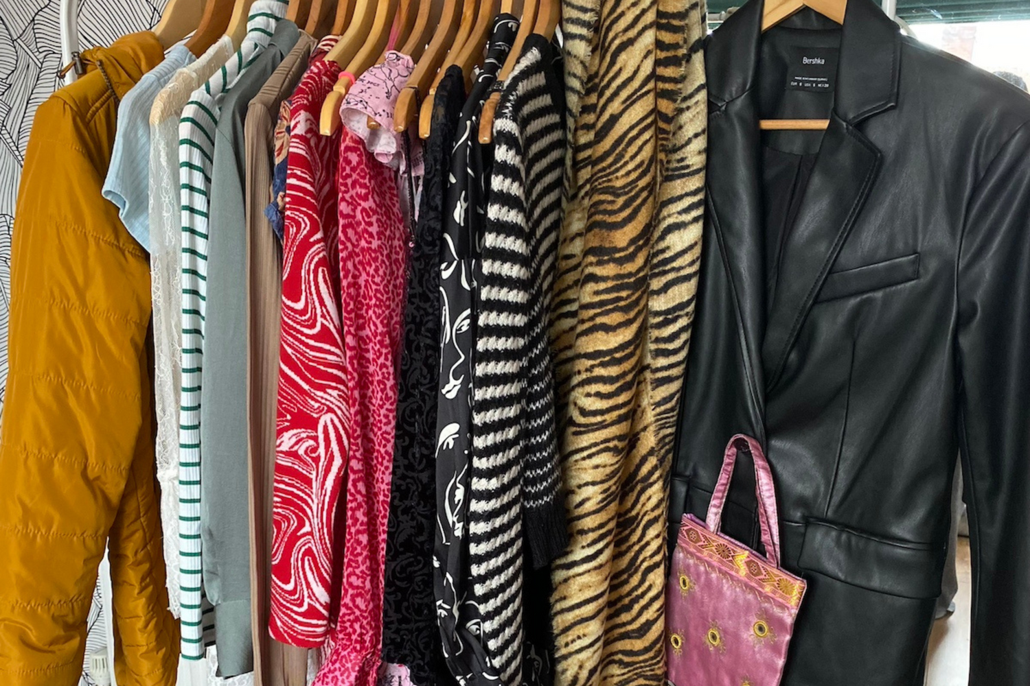 a close up image of women's clothing on a rail with a black and white patterned wallpaper in the background