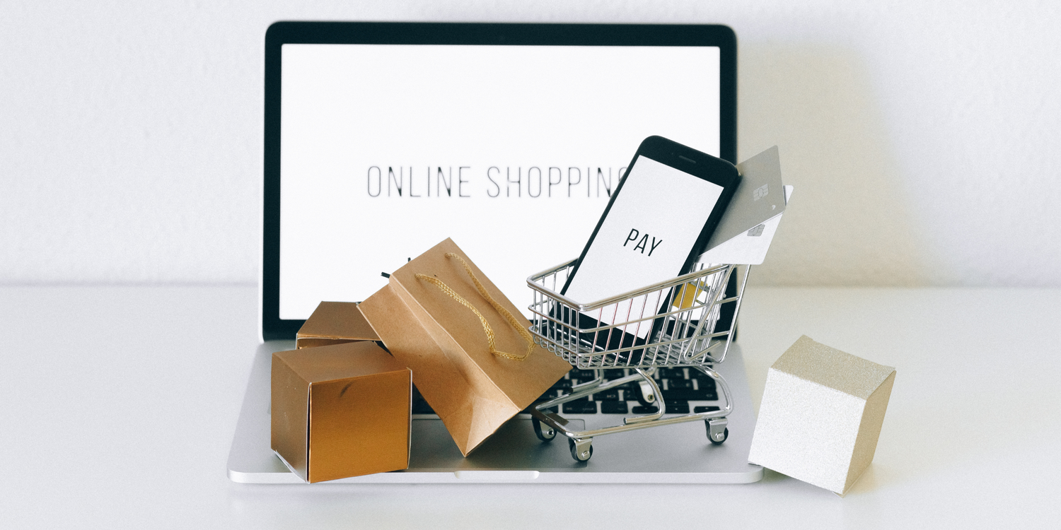 Computer with 'online shopping' on the screen and mini shopping trolly on the keyboard