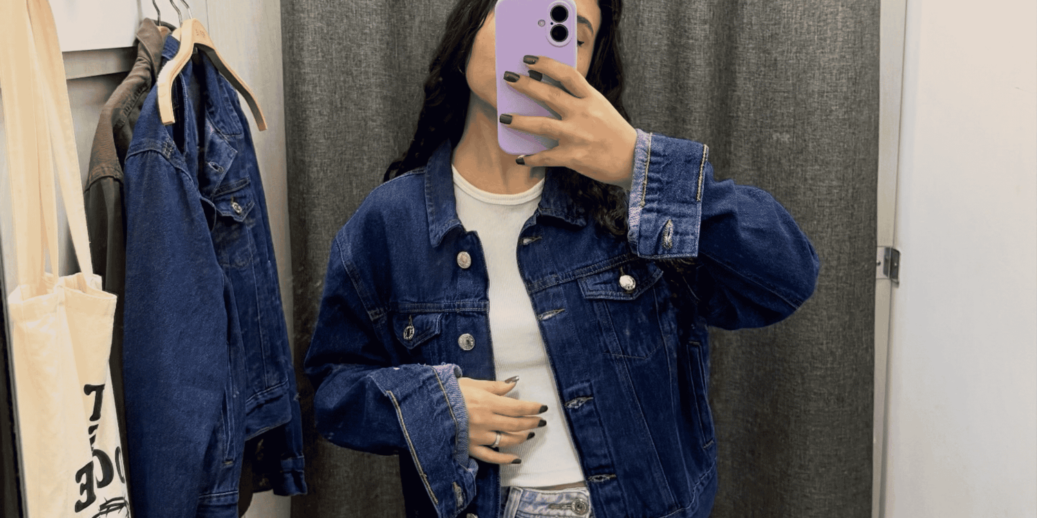 woman taking mirror selfie with blue denim jacket on