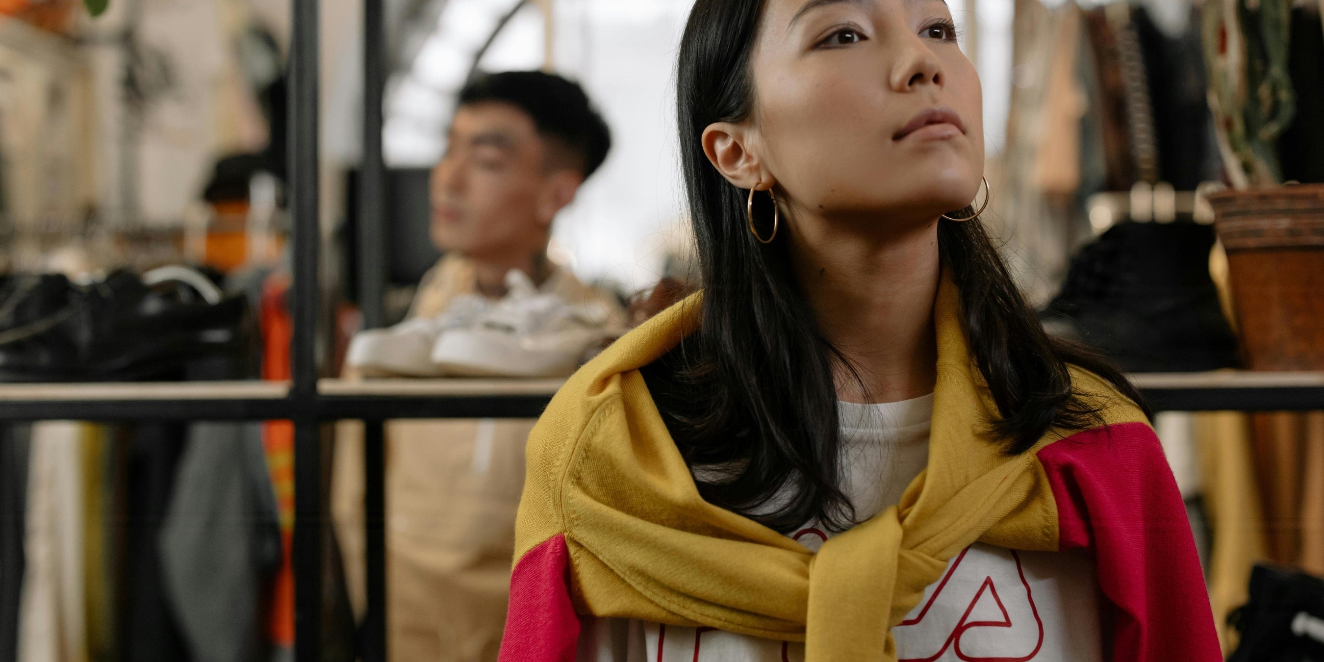 woman looking up towards a shelf in a clothing shop
