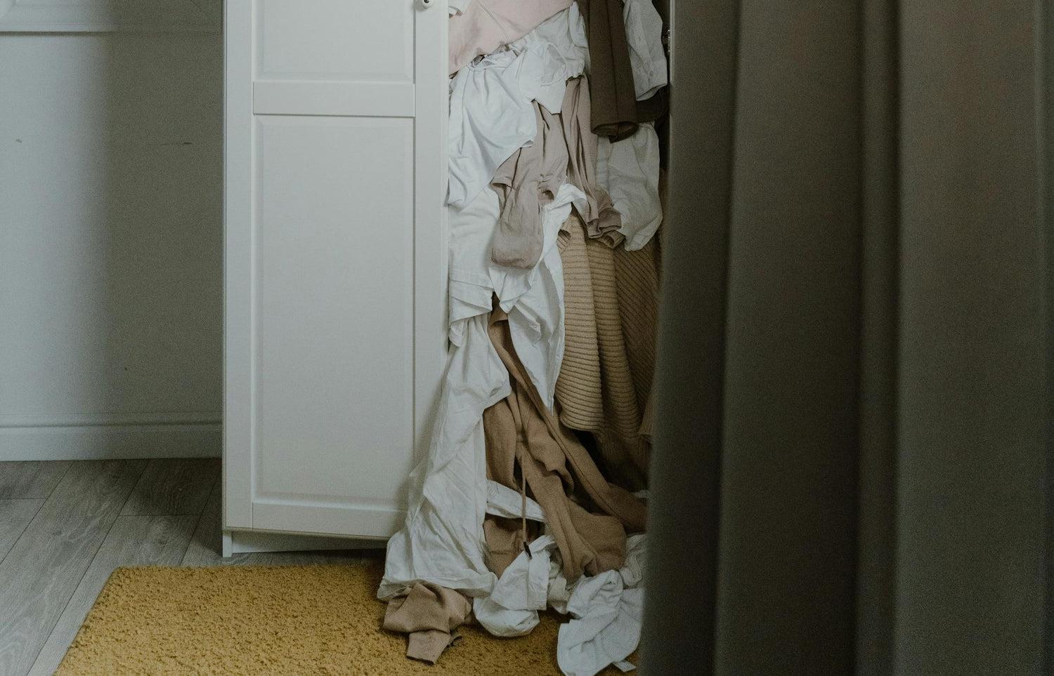 clothes falling out of white wardrobe onto the floor
